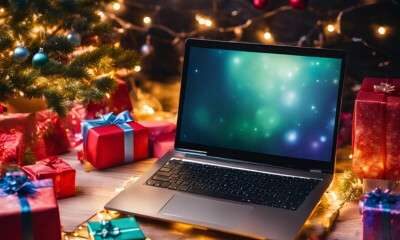 Computer sotto l'albero di natale con lucine e palline